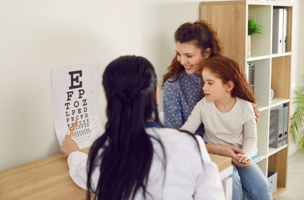 A young girl sits on her mom's lap as she does a visual acuity test to help determine if she has a myopia.