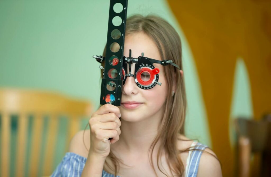 Patient undergoing vision therapy using an eye testing device, holding a line of magnifying lenses.