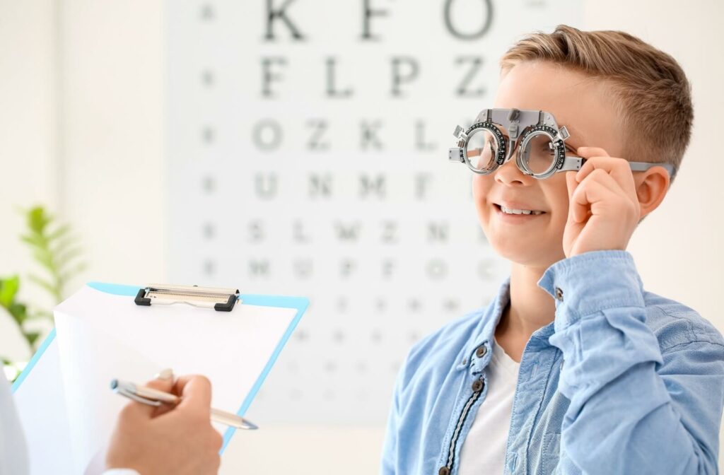 Smiling child wearing a phoropter during a routine eye exam.